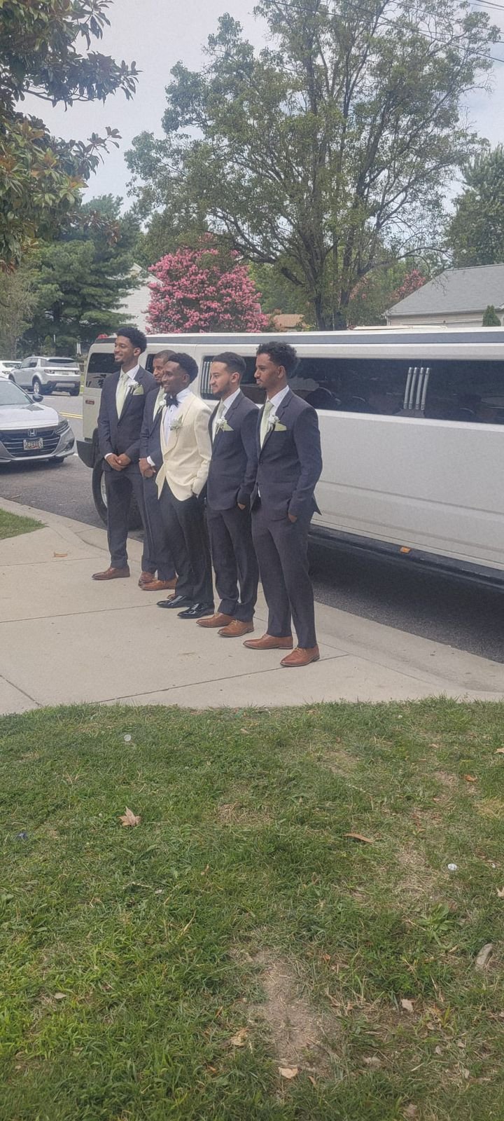Wedding party members in formal attire standing beside a white Hummer Stretch Limousine