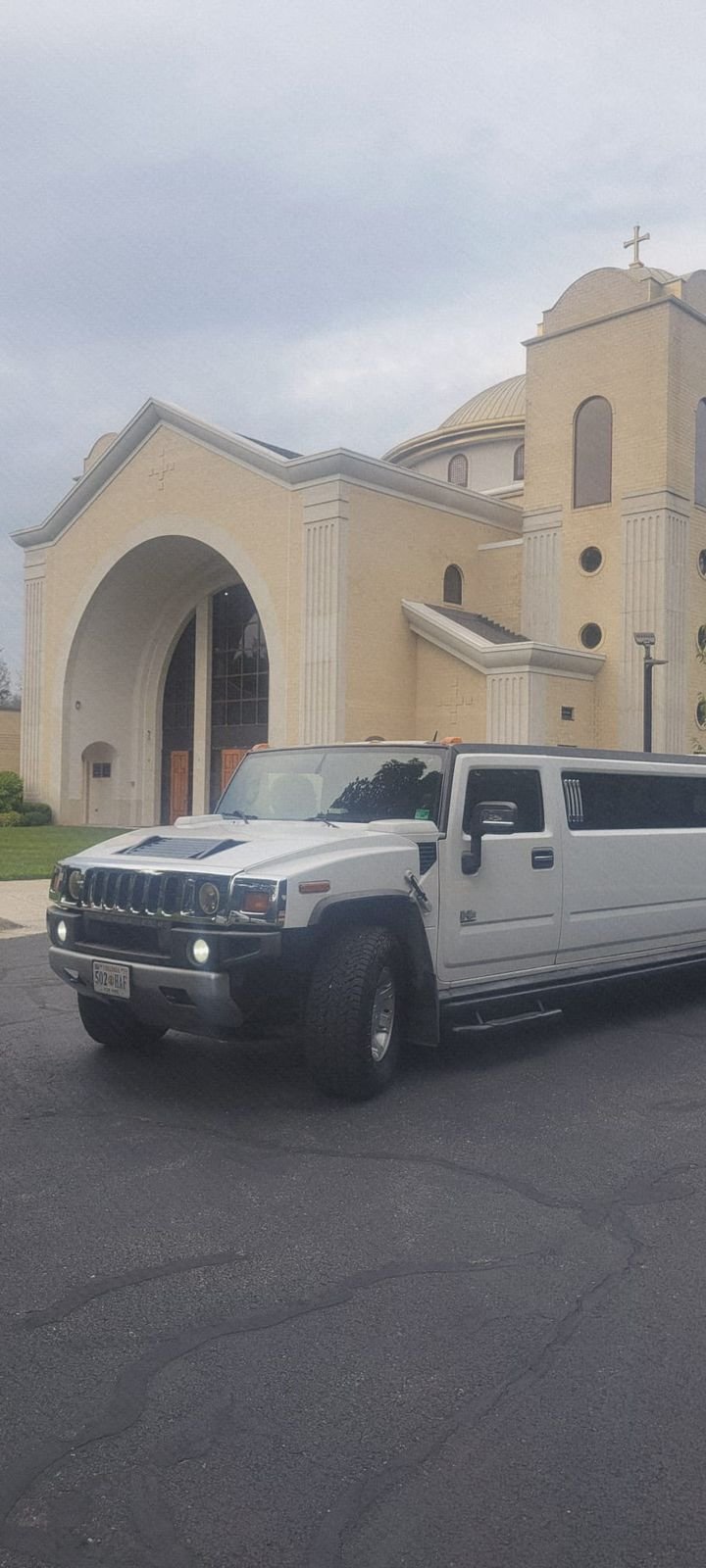 White Hummer Stretch Limousine parked outside a church for wedding transportation